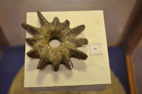 Club-head: Volcanic stone: This star-shaped stone club-head probably dates from the time of early settlements in the region, many hundreds of years ago. Similar club-head have been found elsewhere in Asia, the Pacific, and in South America, but this is the only example yet to be found in Laos. Originally mounted on a stick to be used as a weapon, it probably later took on a ritual significance as an amulet or ceremonial implement. The war stone shaped with careful chipping and polishing, and the central hole is ground down with small stone and sand. This volcanic stone does not seem to be common in Laos, so perhaps this item has been traded from elsewhere, which would also account for its rarity.