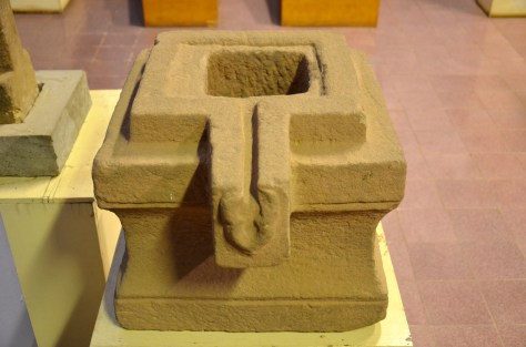 Yoni: Sandstone, 9-14th centuries: The yoni, usually used to anchor a linga, represents the equivalent feminine principle of power. Whilst the linga is a symbol of Shiva and his generative role in creation, the yoni represents nurture and fertility. Surrounding the cavity for the linga is a channel for ablutionary waters to flow through.